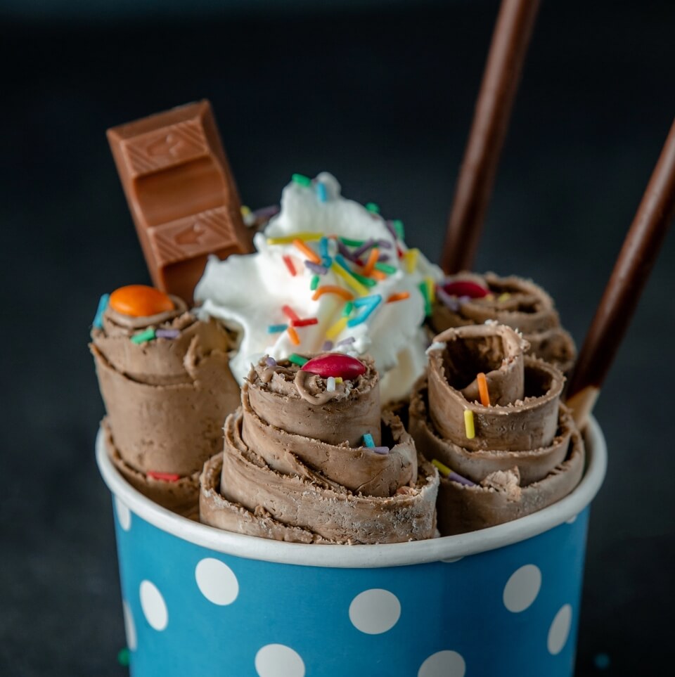 side-view-thai-ice-cream-roll-topped-with-colorful-sprinkles-cardboard-bowl-black-wall (1)